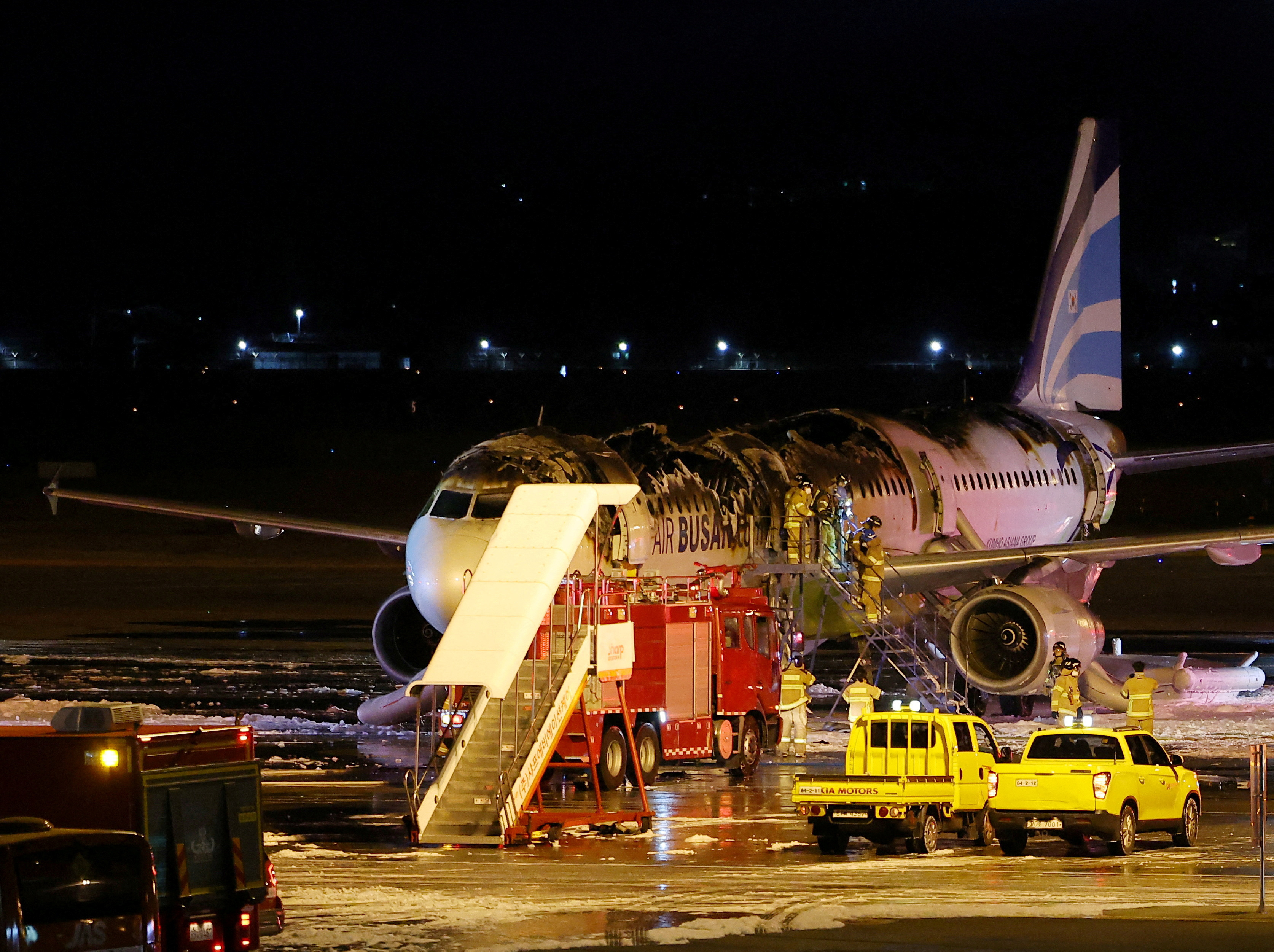 Firefighters work on an Air Busan plane that caught fire at Gimhae International Airport in Busan