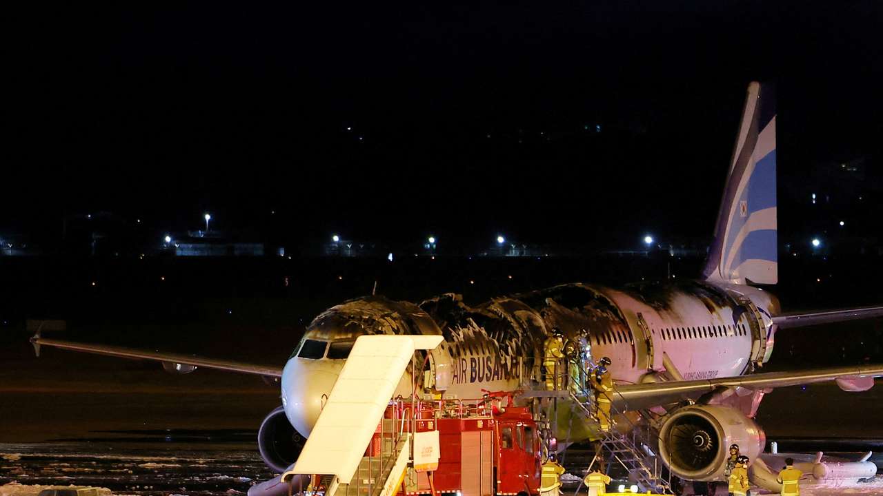 Firefighters work on an Air Busan plane that caught fire at Gimhae International Airport in Busan