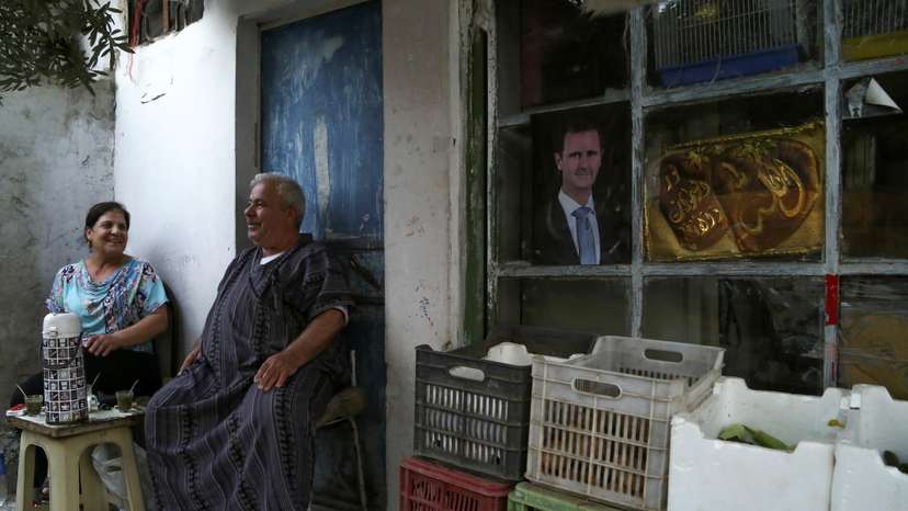 People sit outside their house during a power cut in Damascus