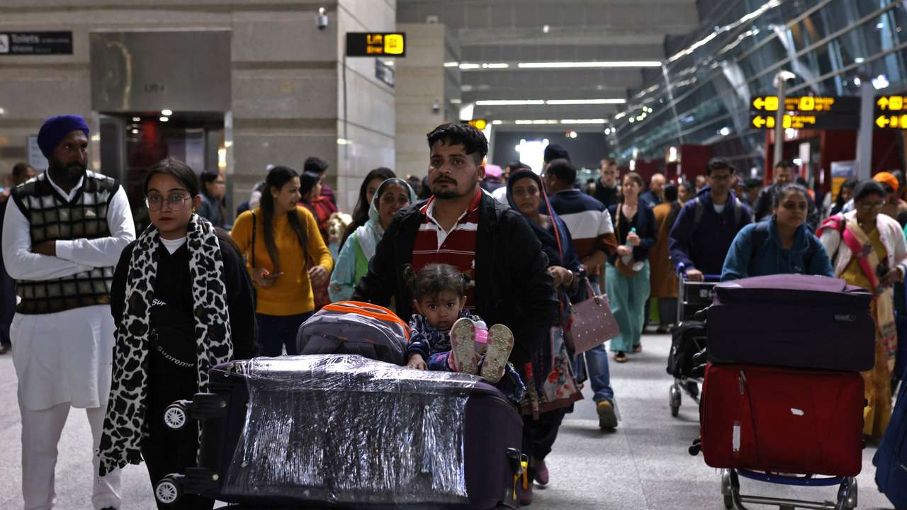 Travellers push trolleys with their luggage at the departure area of Indira Gandhi International Airport in New Delhi
