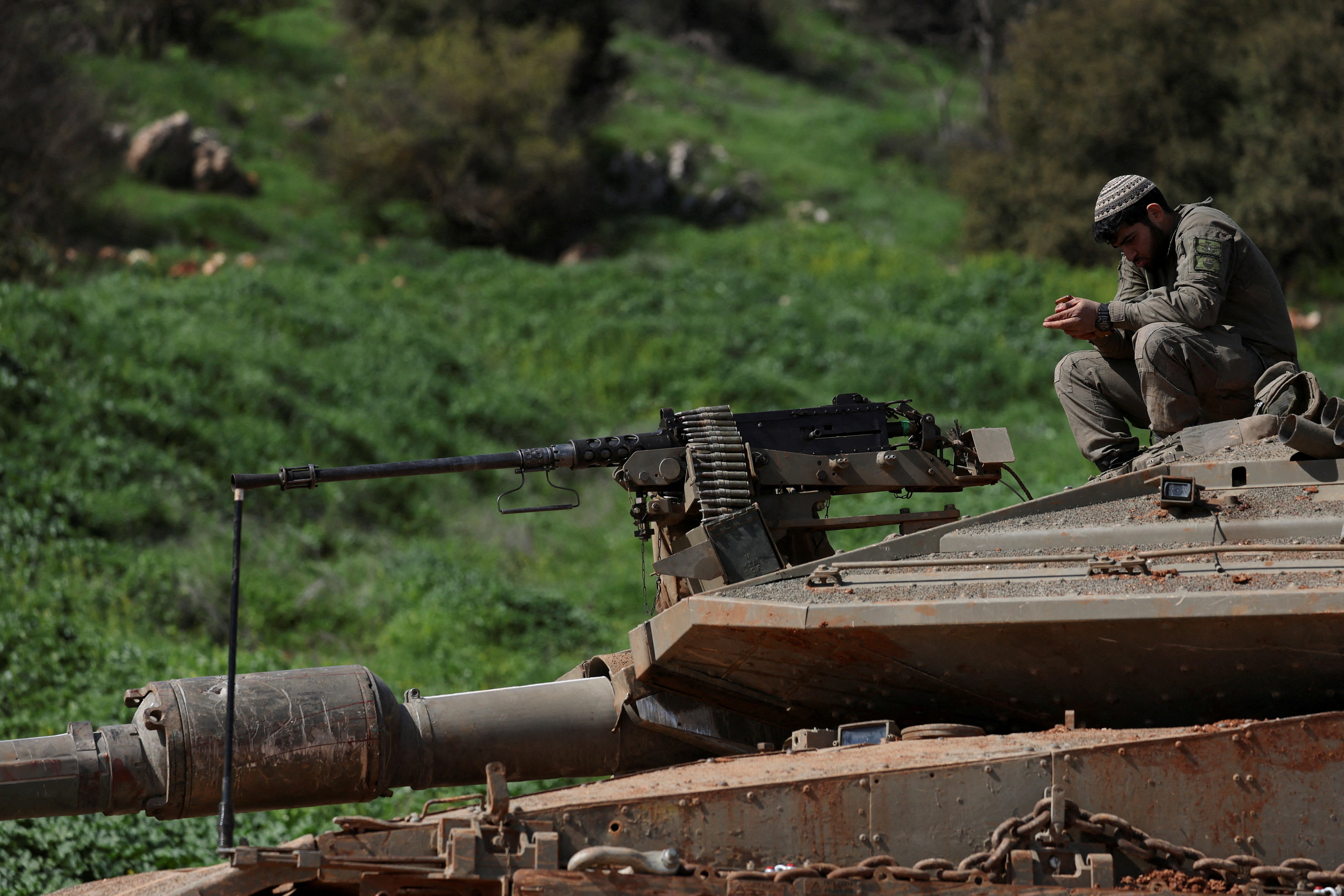 Israeli soldiers sit on a tank on the Israeli side of the border with Lebanon, amid escalation between Hezbollah and Israel