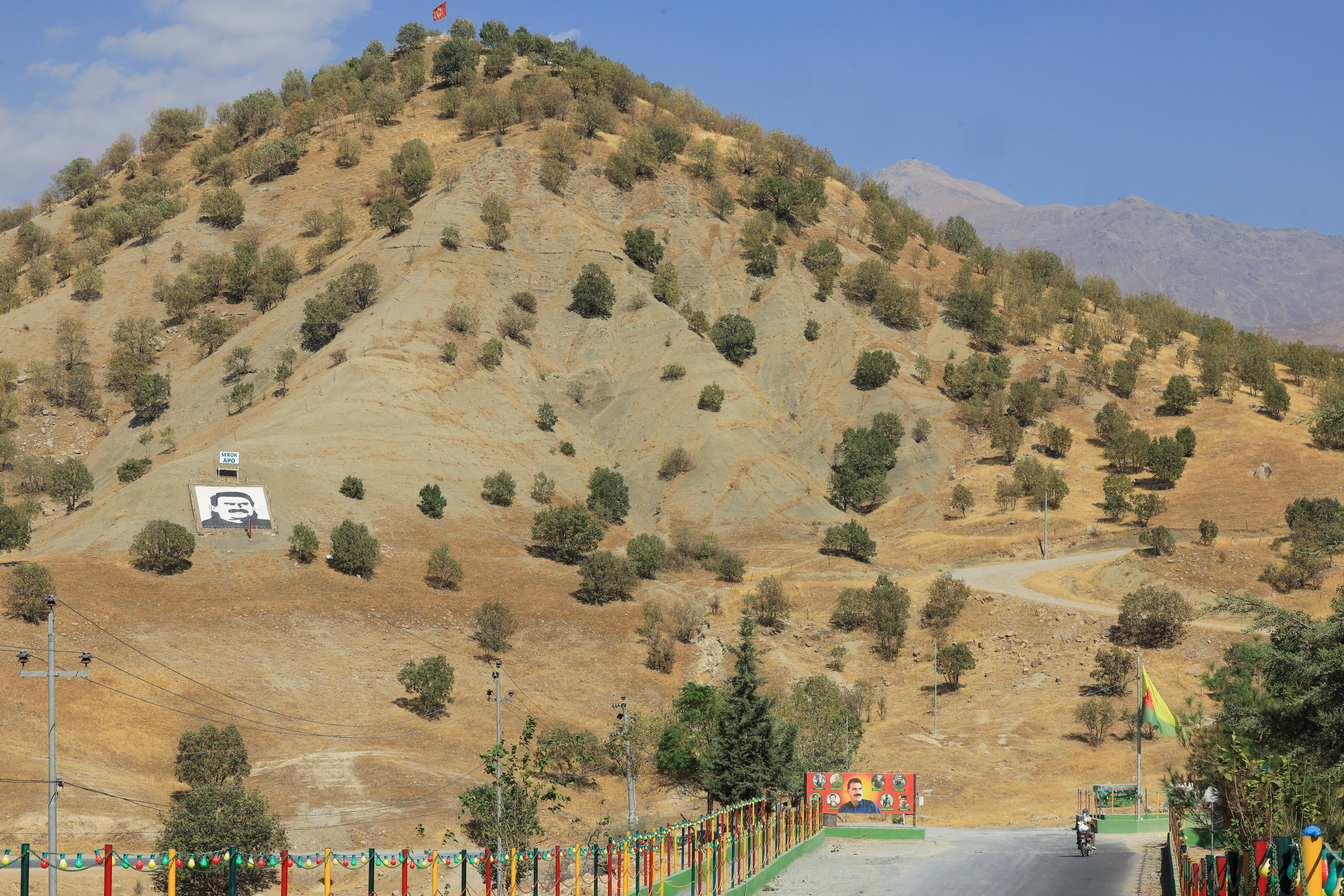 A portrait of jailed Kurdistan Workers Party leader Abdullah Ocalan and a sign with the words "Serok Apo," are displayed on a hillside in the Qandil mountains