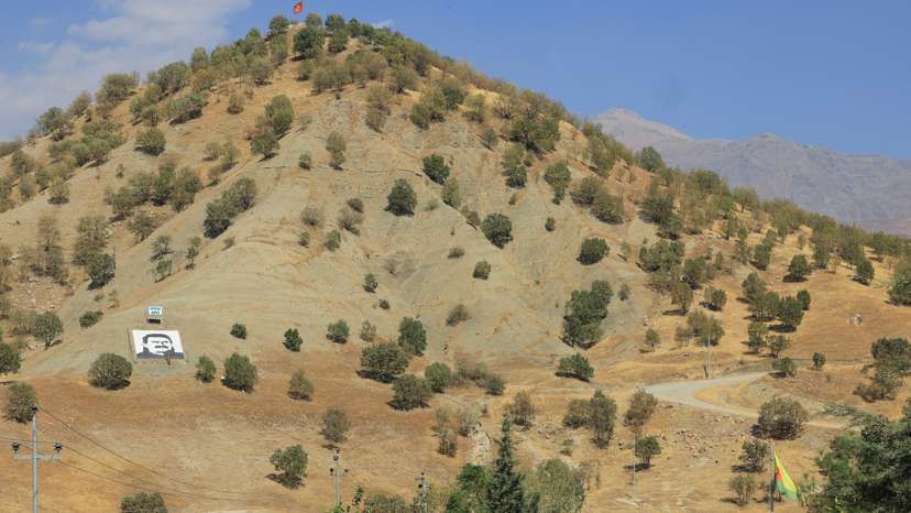 A portrait of jailed Kurdistan Workers Party leader Abdullah Ocalan and a sign with the words "Serok Apo," are displayed on a hillside in the Qandil mountains