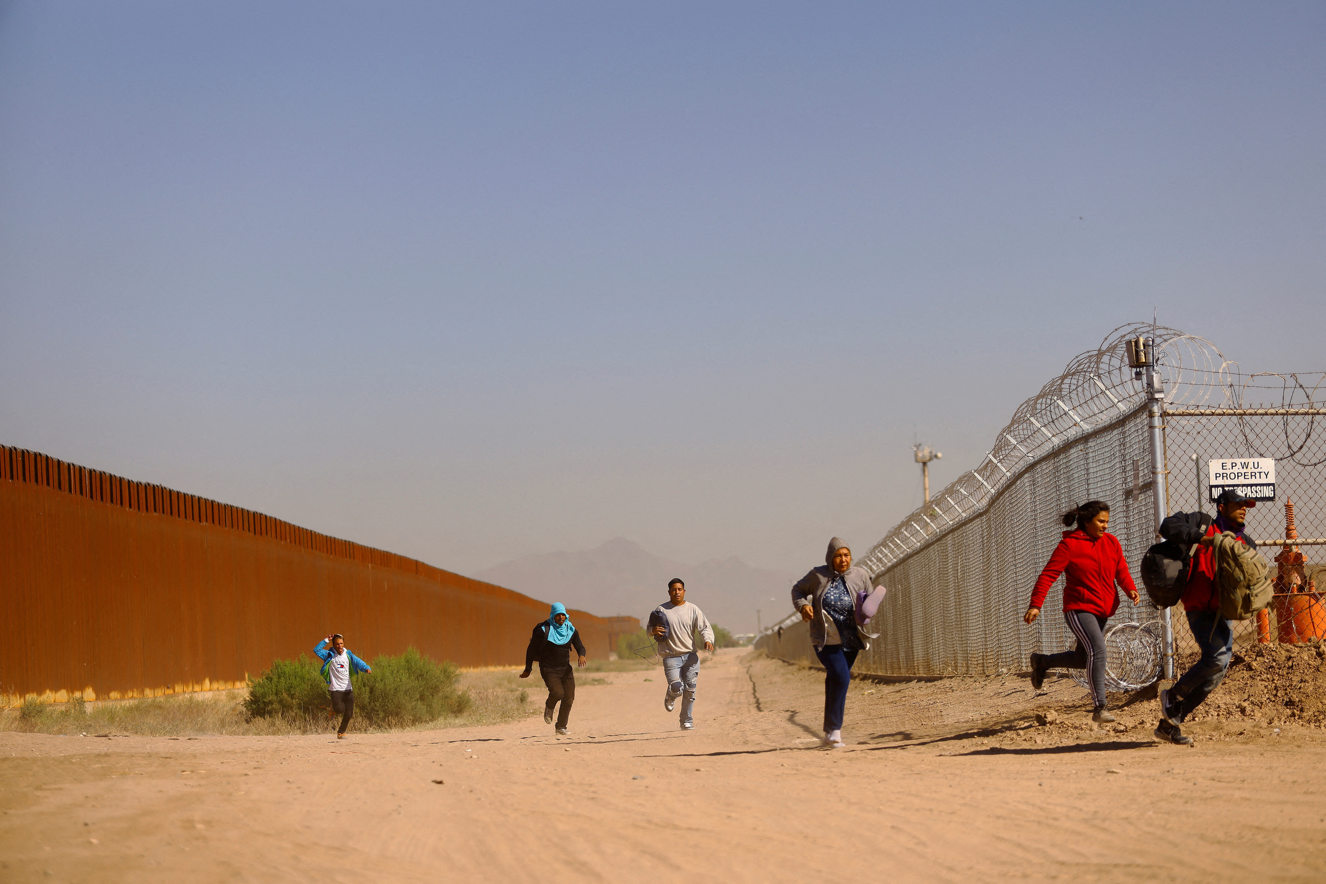 FILE PHOTO: Migrants run to hide from the U.S. Border Patrol and the Texas National Guard  in El Paso