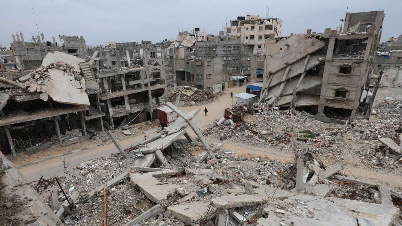 Palestinians walk surrounded by the rubble of houses destroyed in Israeli strikes during the war, in Khan Younis
