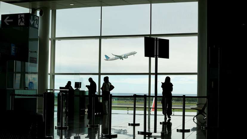 People line up to check in a flight as a plane takes off at Josep Tarradellas Barcelona–El Prat Airport, in Barcelona Spain