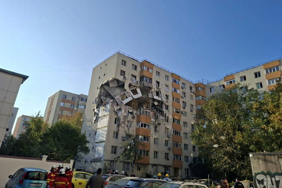 People look at the damage caused by an explosion at an apartment block, in Bucharest