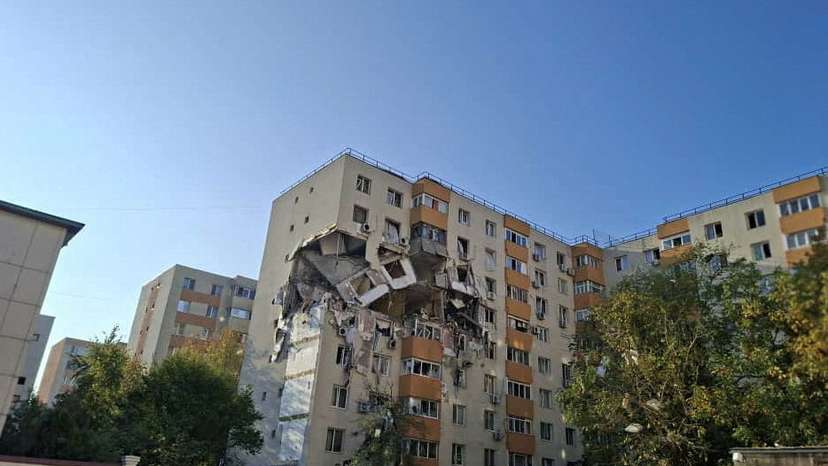 People look at the damage caused by an explosion at an apartment block, in Bucharest