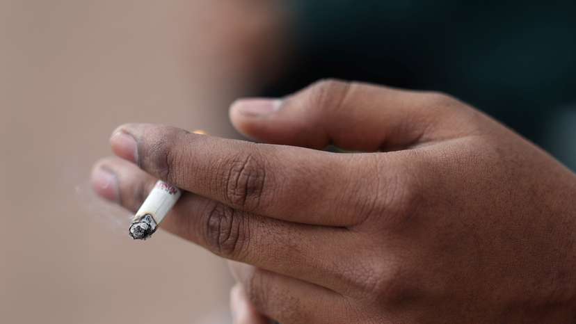 A man holds his cigarette as he smokes in London