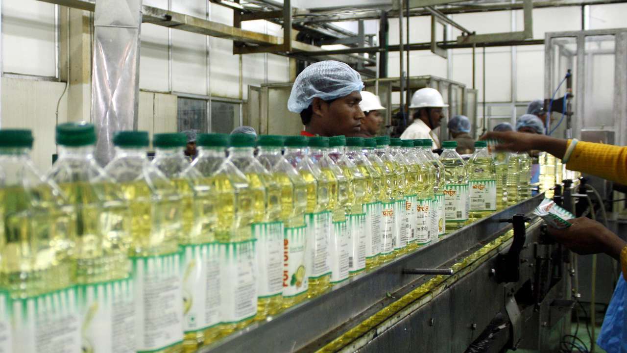 Employees fill plastic bottles with edible oil at an oil refinery plant of Adani Wilmar Ltd in Mundra