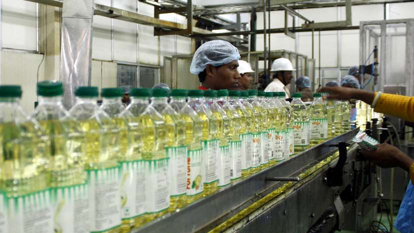 Employees fill plastic bottles with edible oil at an oil refinery plant of Adani Wilmar Ltd in Mundra