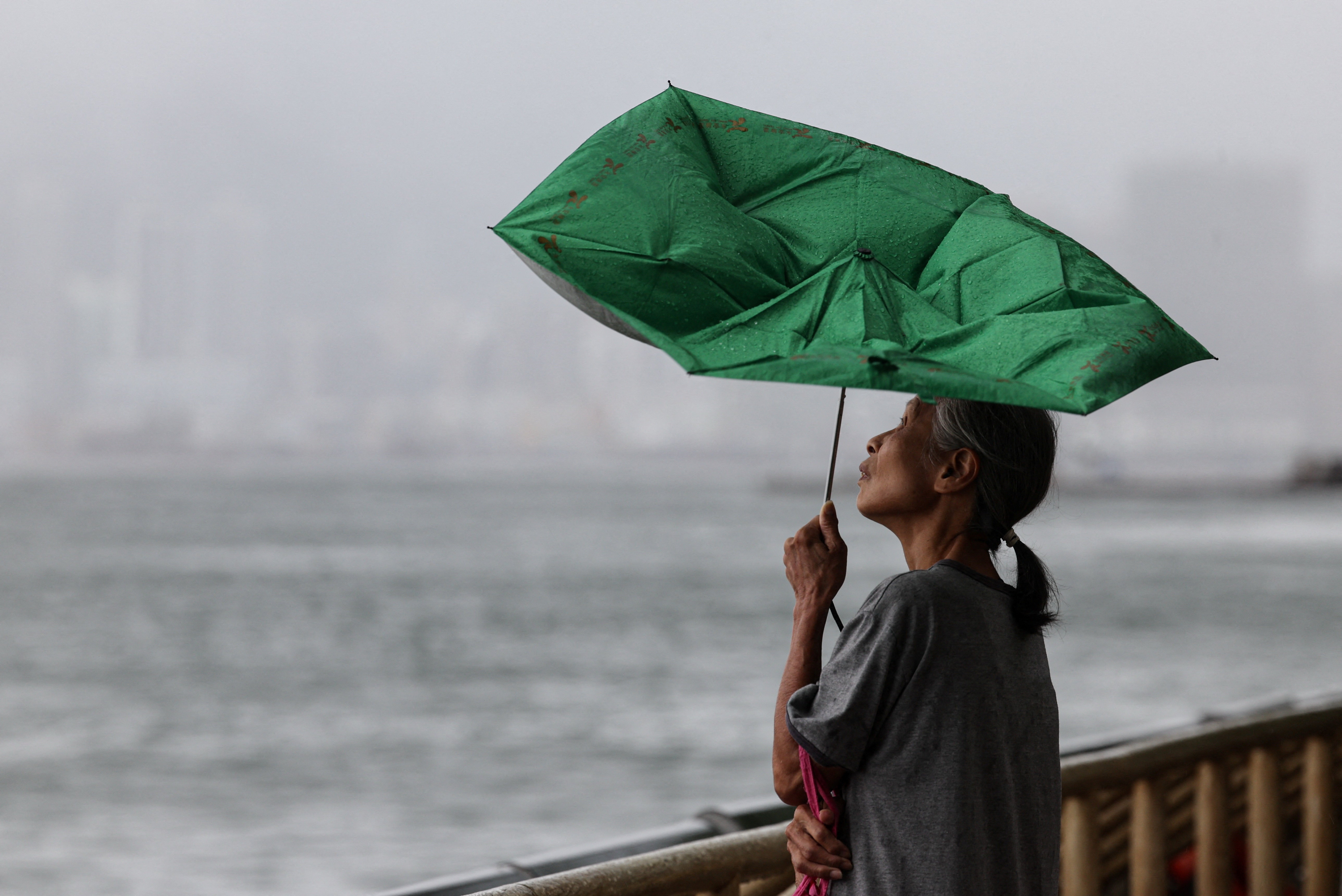 A woman holds an umbrella inverted by winds as Tropical Storm Tapah approaches in Hong Kong