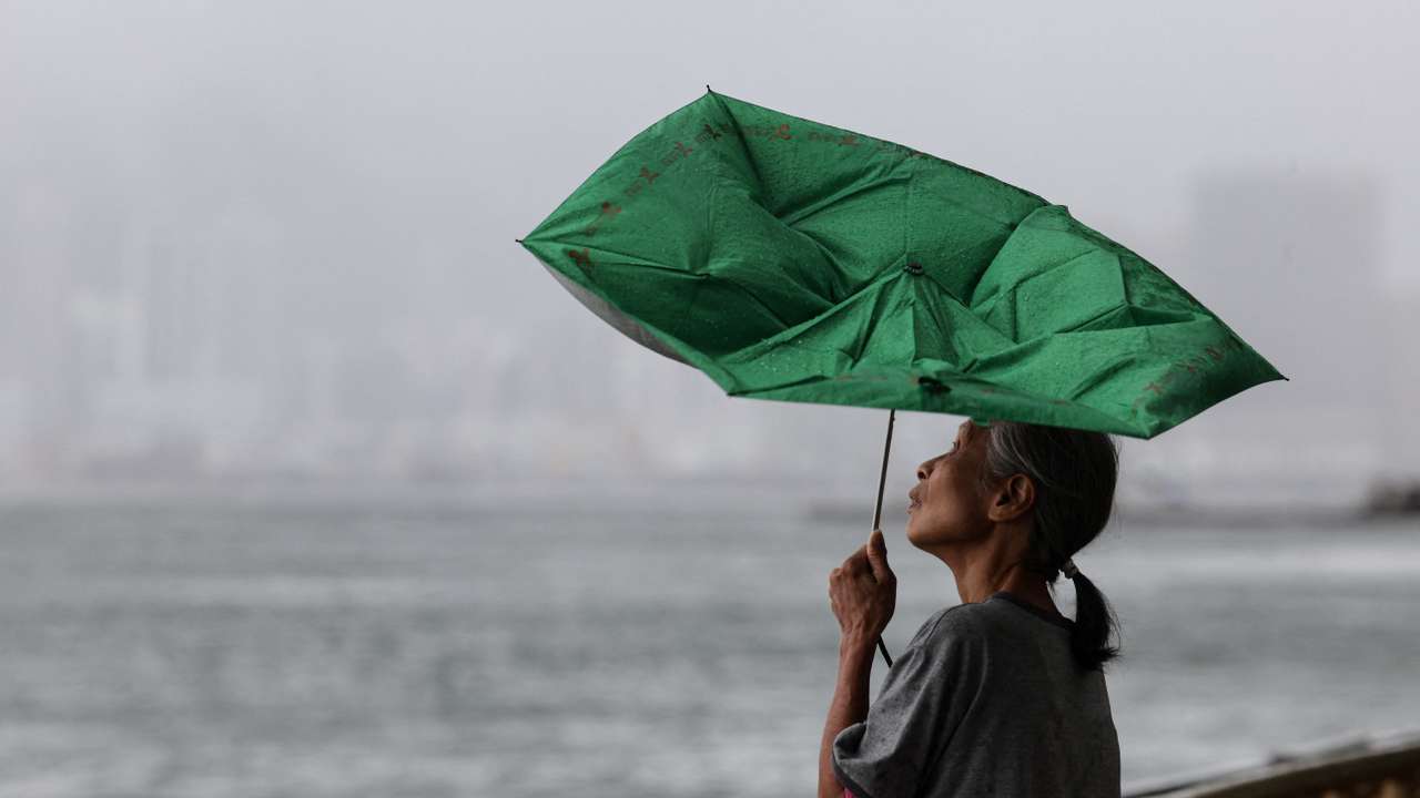 A woman holds an umbrella inverted by winds as Tropical Storm Tapah approaches in Hong Kong