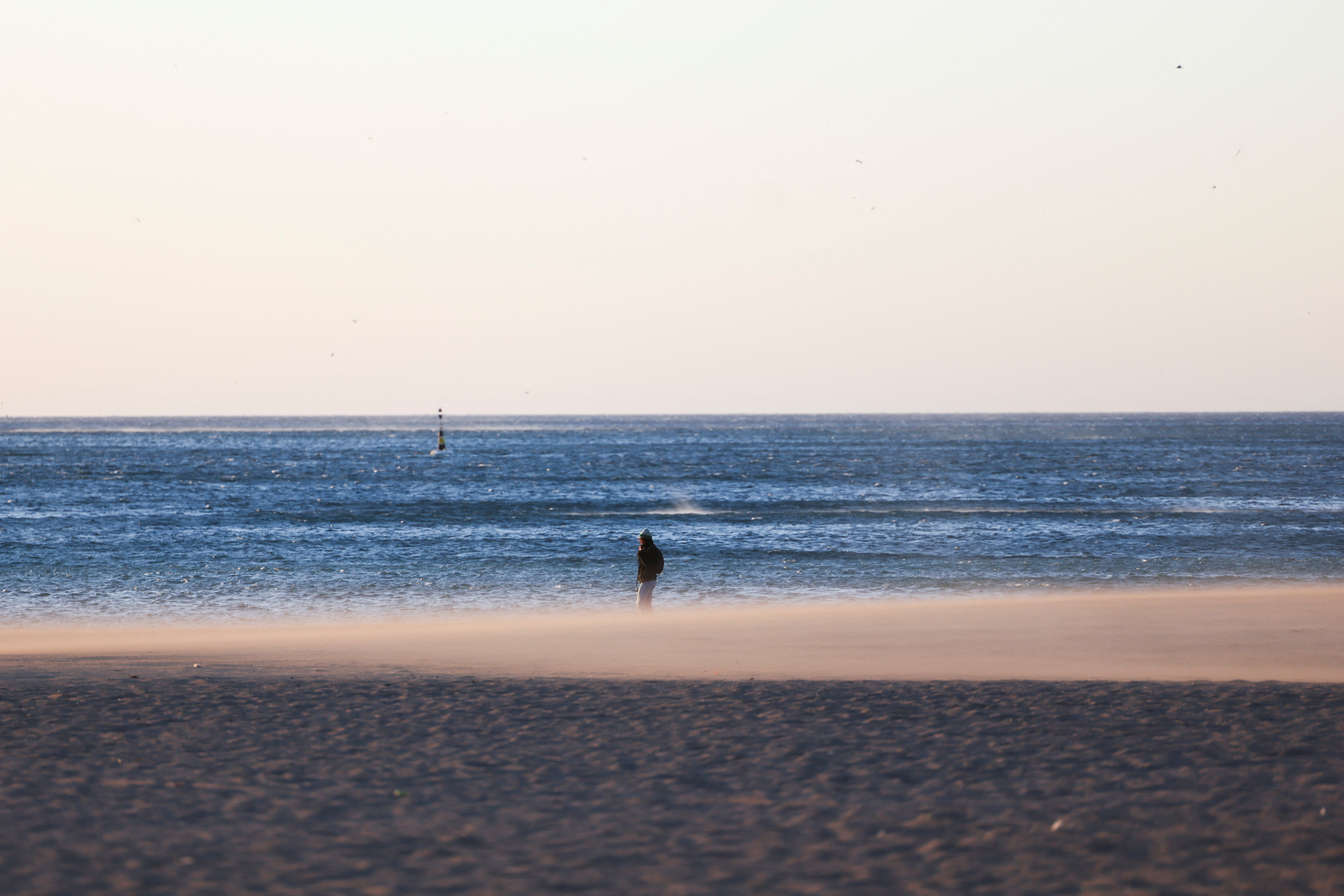 A woman walks on the Barceloneta beach during high winds in Barcelona