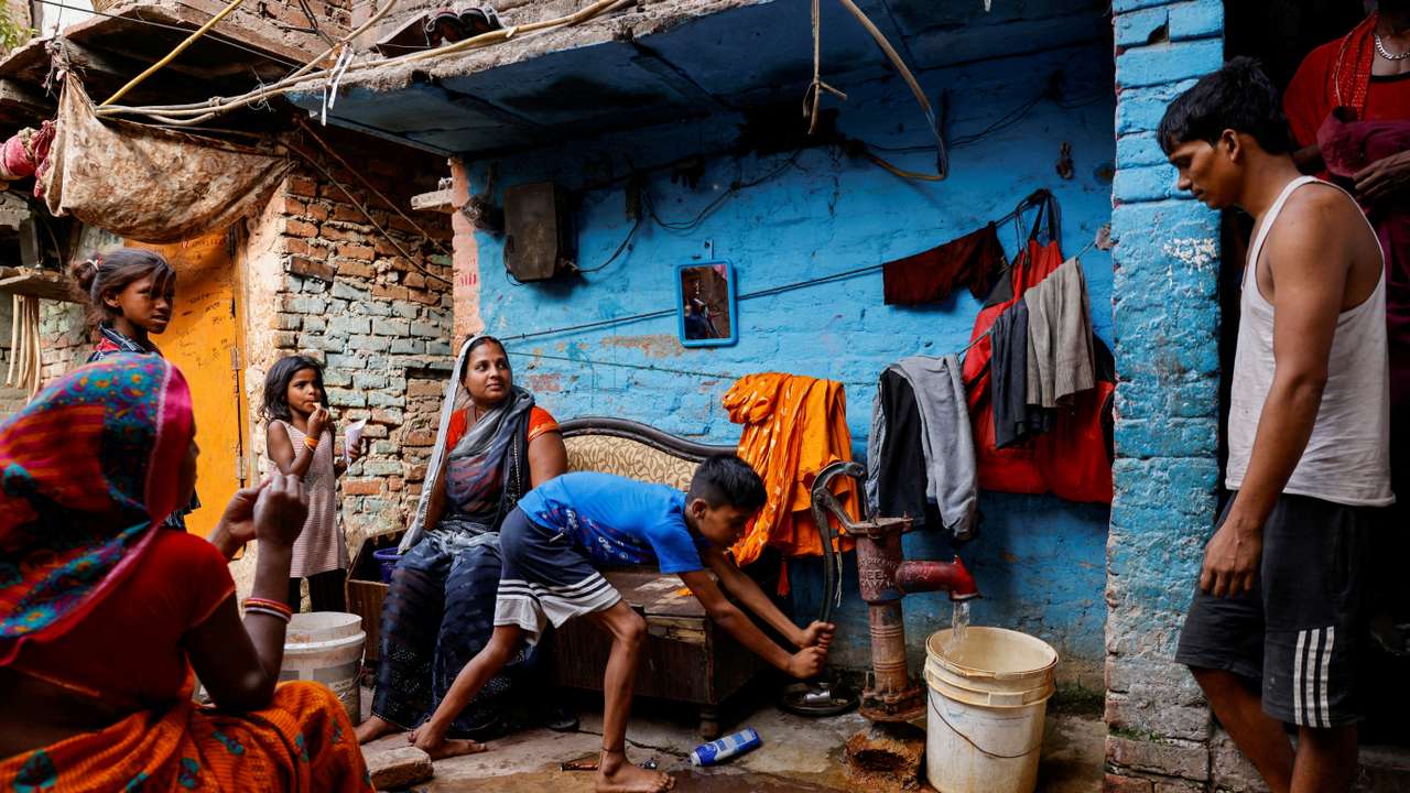 FILE PHOTO: A boy fills water in a container using a hand pump on a hot summer day during a heatwave in New Delhi