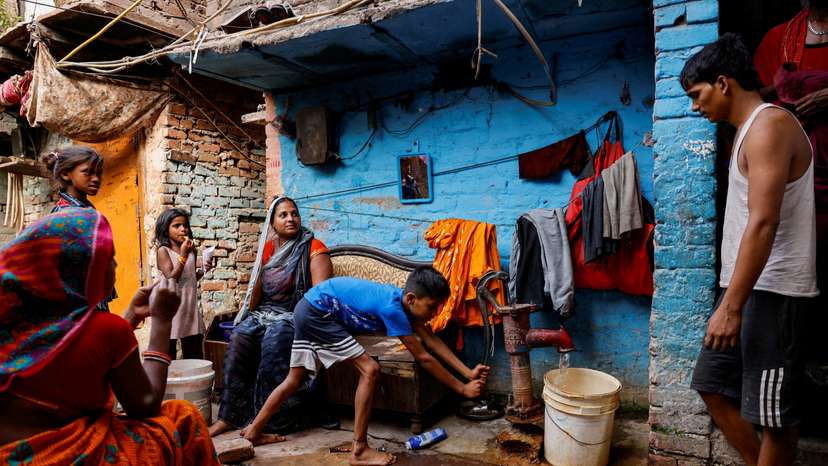 FILE PHOTO: A boy fills water in a container using a hand pump on a hot summer day during a heatwave in New Delhi
