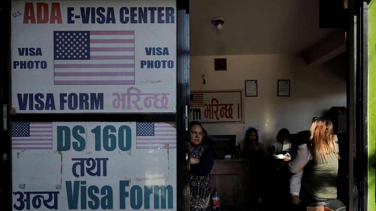 A woman holding a child sits at a visa consultancy, in Kathmandu