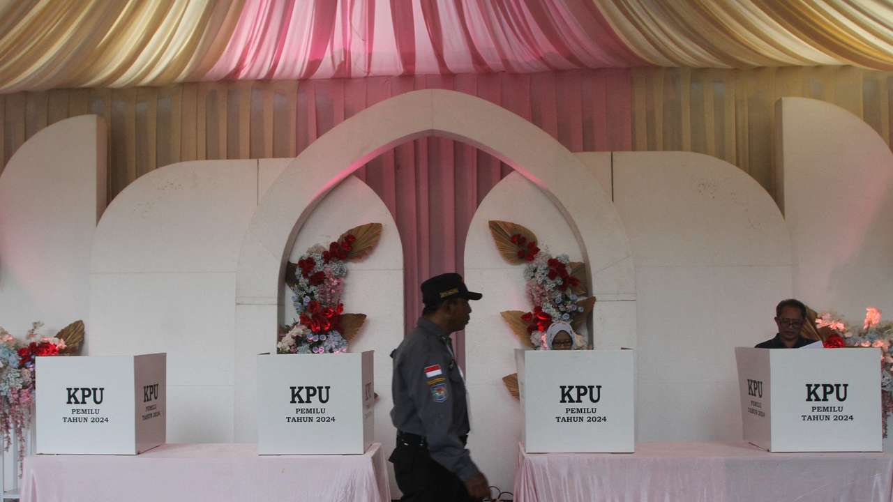 A member of the Linmas civil defence force passes by ballot boxes at a Valentine’s Day themed polling station during the general election in Malang