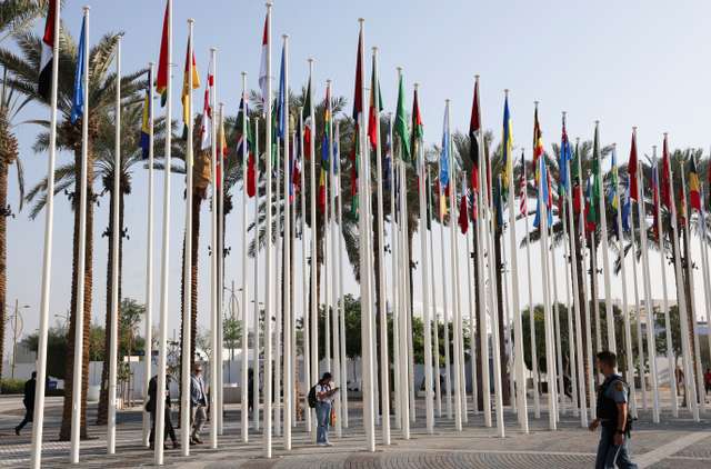 UN security officer walks near the flags at Dubai's Expo City during the United Nations Climate Change Conference (COP28) in Dubai