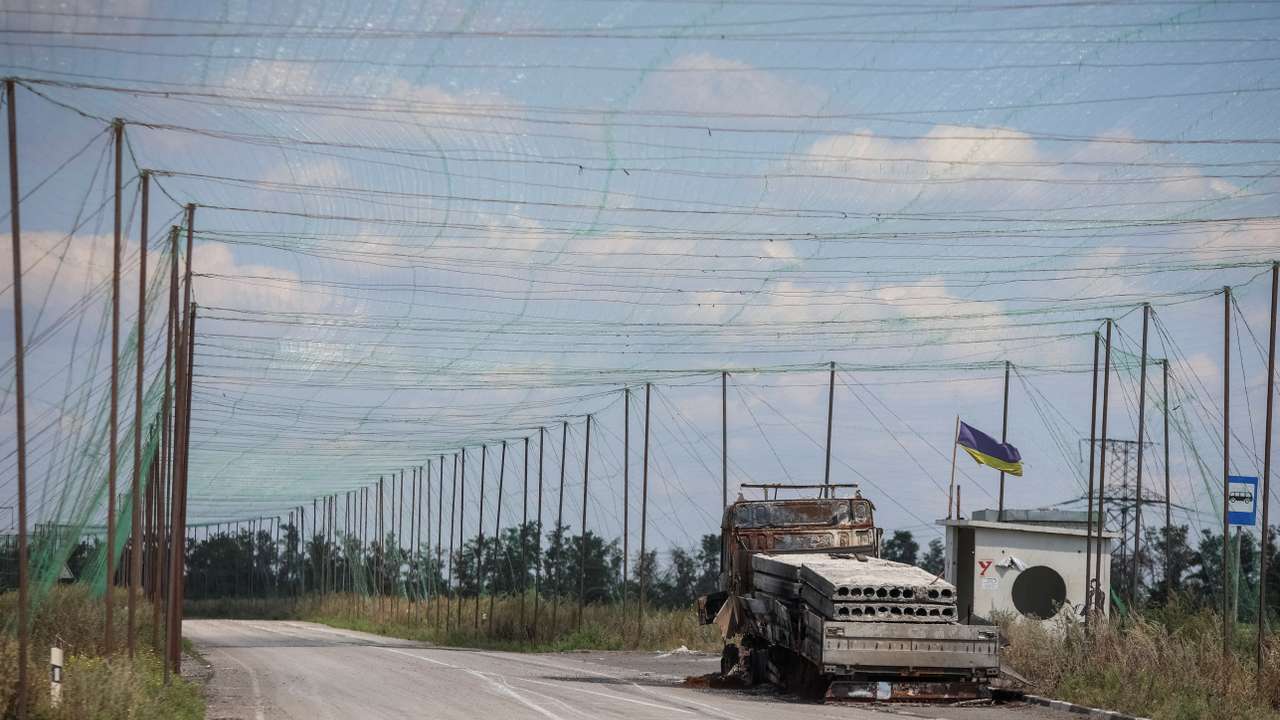 A view shows a burned vehicle and anti-drone nets installed over a road near the frontline town of Dobropillia