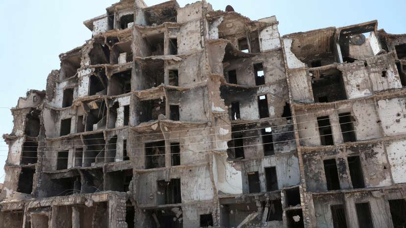 FILE PHOTO: People ride on a motorbike past a damaged building as U.S. President Donald Trump announced that he would order the lifting of sanctions on Syria, in Aleppo