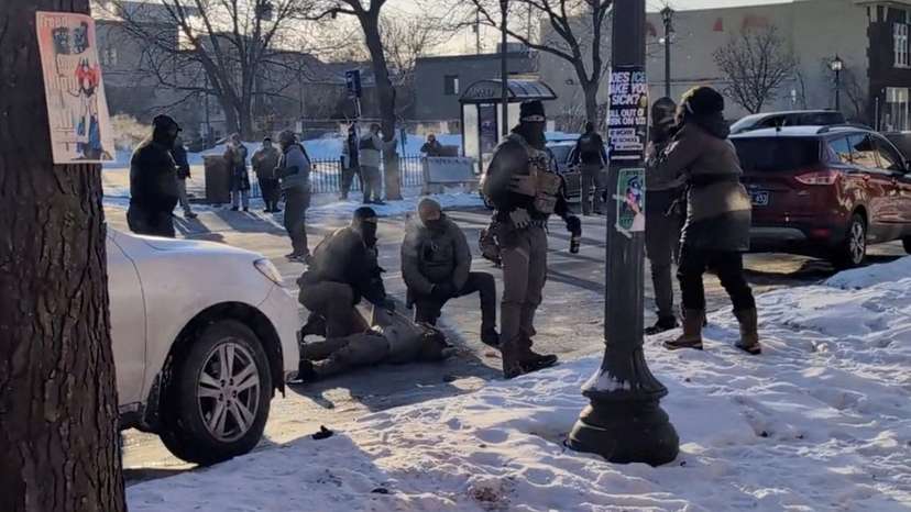 Law enforcement officers kneel next to the body of a man who was shot when federal agents were trying to detain him in Minneapolis