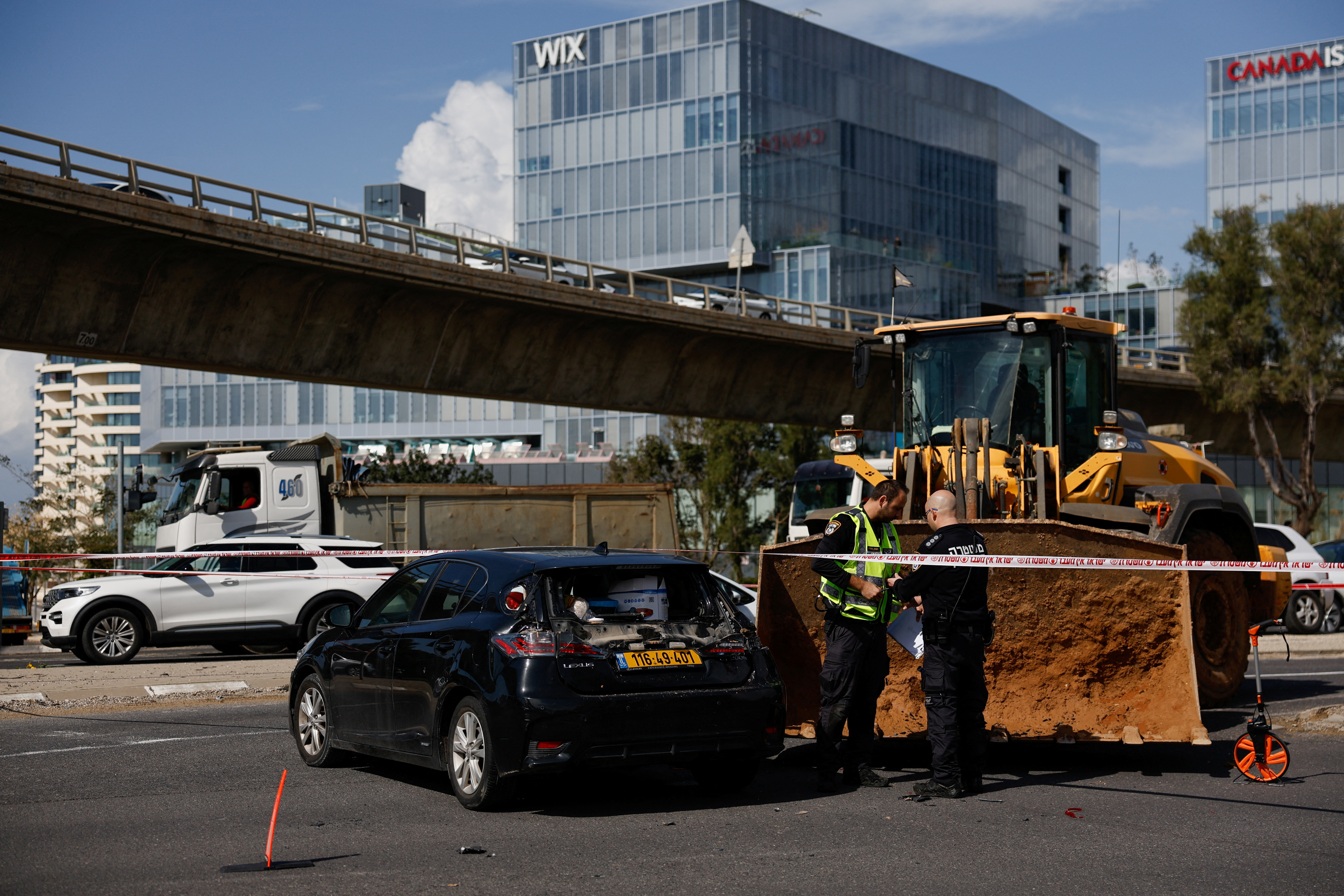 Israeli personnel work near a tractor at the scene of an incident in Tel Aviv