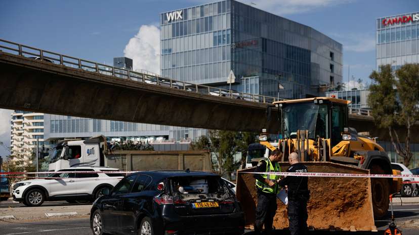 Israeli personnel work near a tractor at the scene of an incident in Tel Aviv