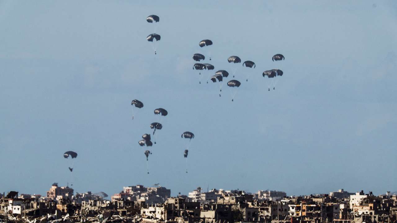 Packages dropped from a military aircraft fall towards northern Gaza, as seen from Israel