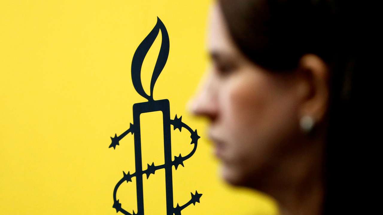 The logo of Amnesty International is seen next to director of Mujeres En Linea Luisa Kislinger, during a news conference in Caracas