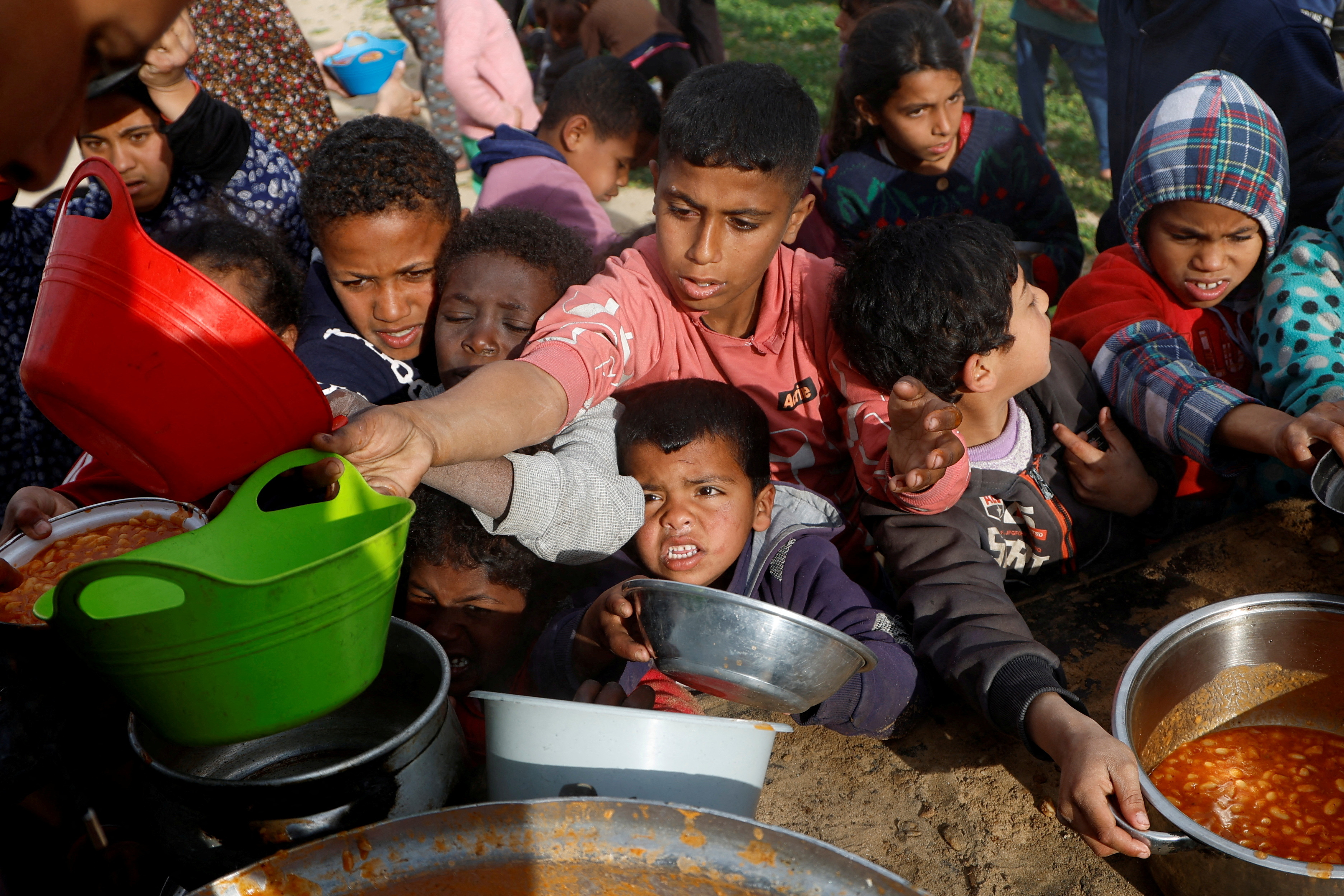 Palestinians gather to receive food cooked by a charity kitchen, in Khan Younis