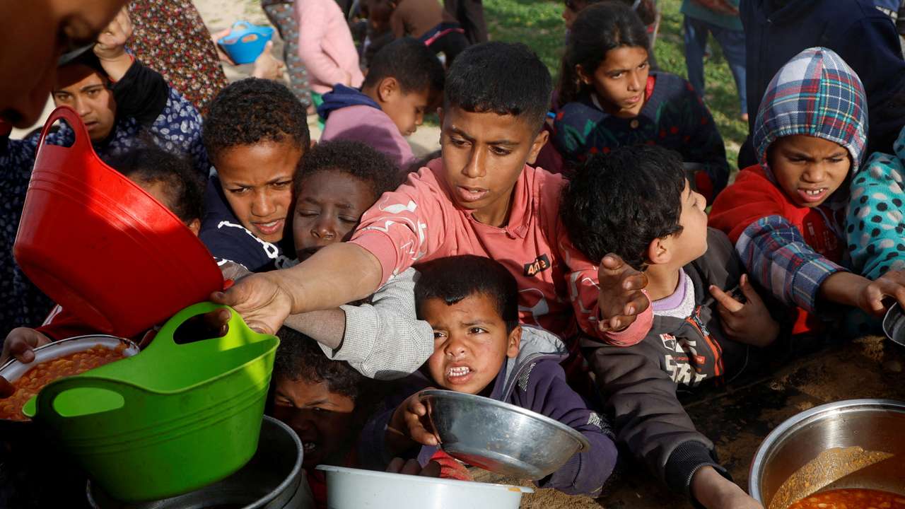 Palestinians gather to receive food cooked by a charity kitchen, in Khan Younis