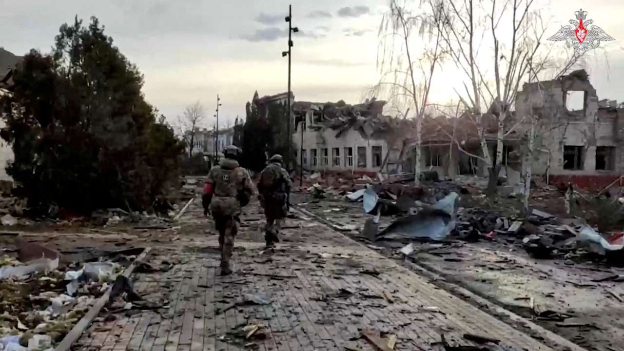 FILE PHOTO: Russian service members walk past a destroyed building in Sudzha