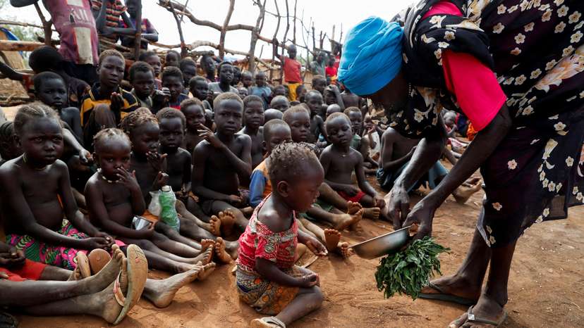 FILE PHOTO: Asha Kano Kavi, an internally displaced woman from Kadugli, serves wild boiled leaves for food to orphaned children at the Bruam IDP Camp in the Nuba Mountains, South Kordofan, Sudan