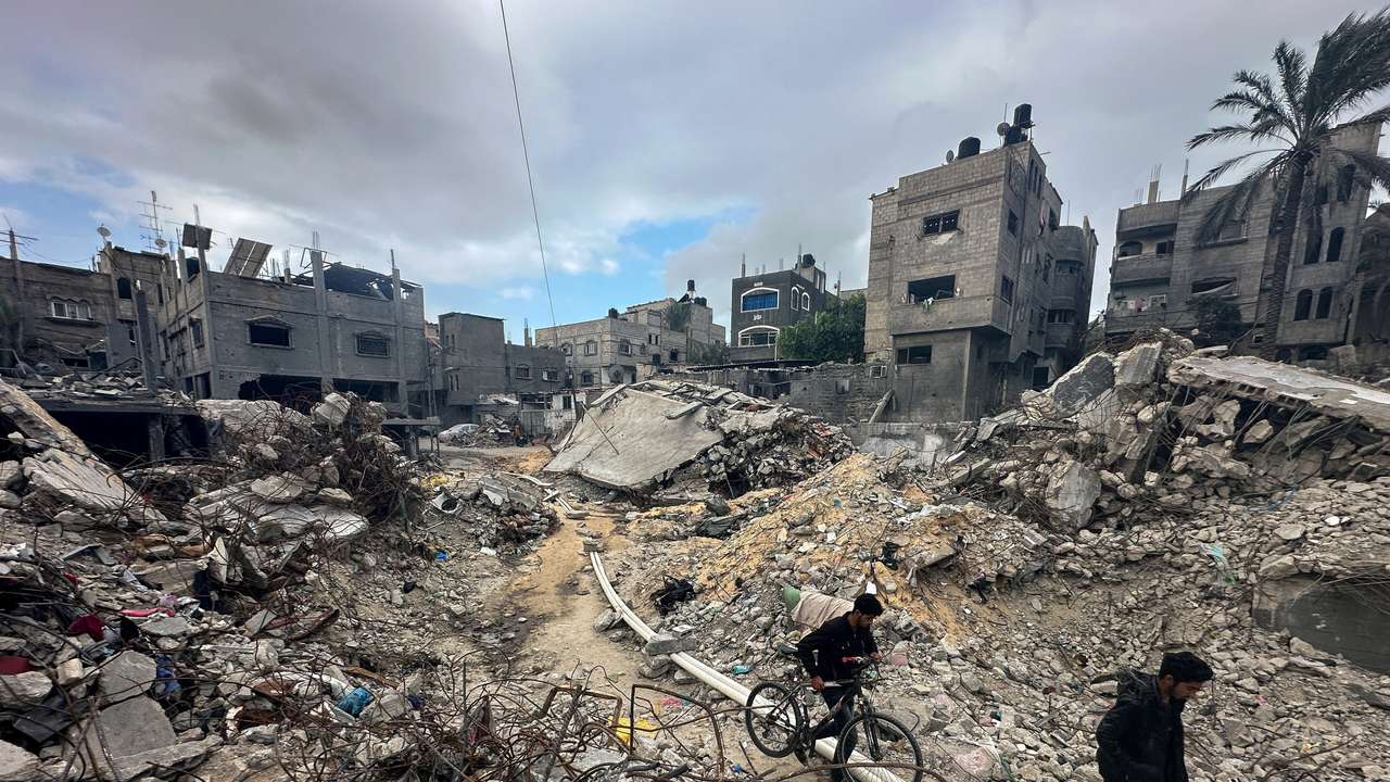 Palestinians inspect houses, destroyed in Israeli strikes during the conflict, at Khan Younis refugee camp