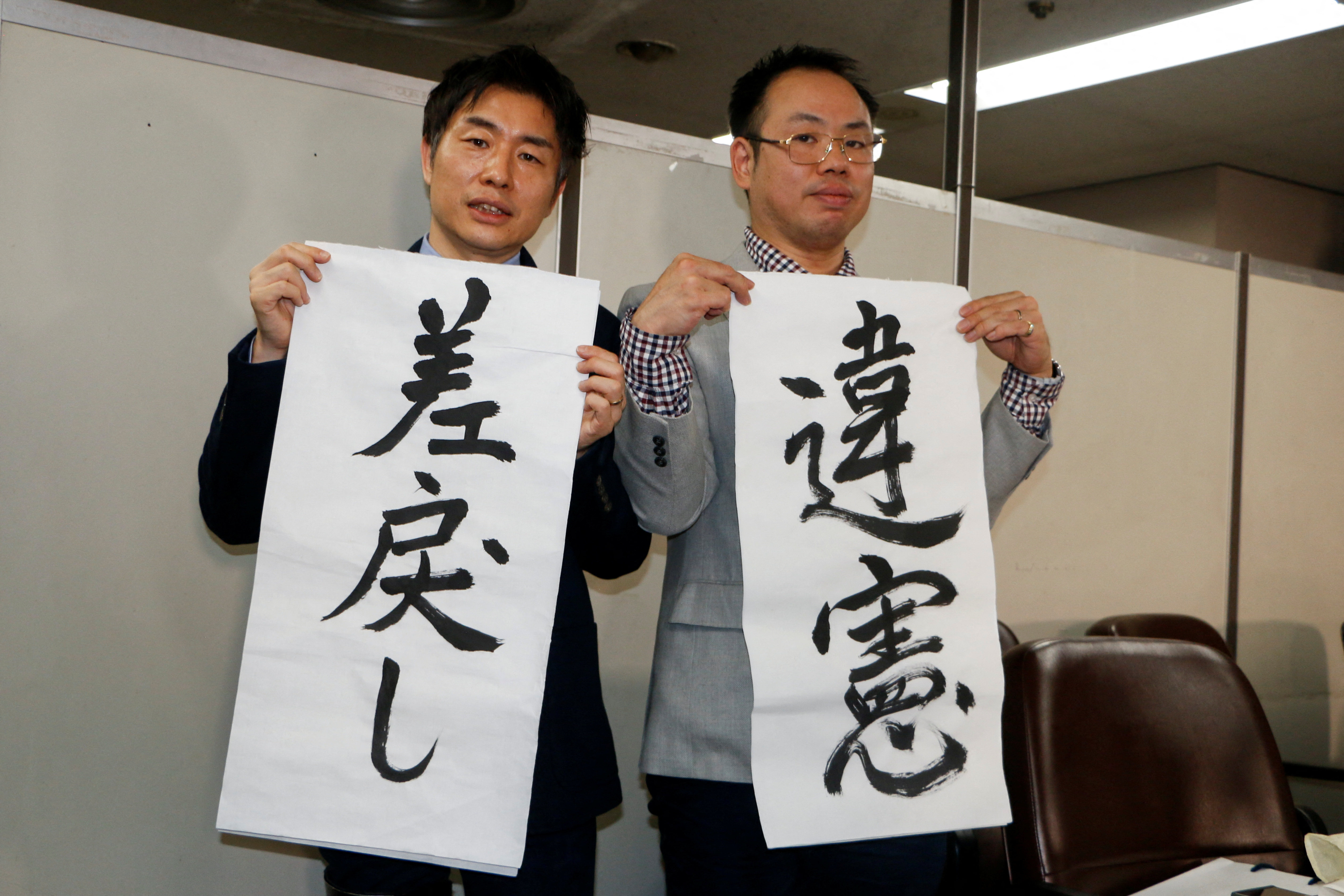 The Plaintiff's lawyers, Kazuyuki Minami and Masafumi Yoshida, hold banners that read "returned" and "unconstitutional", in Tokyo