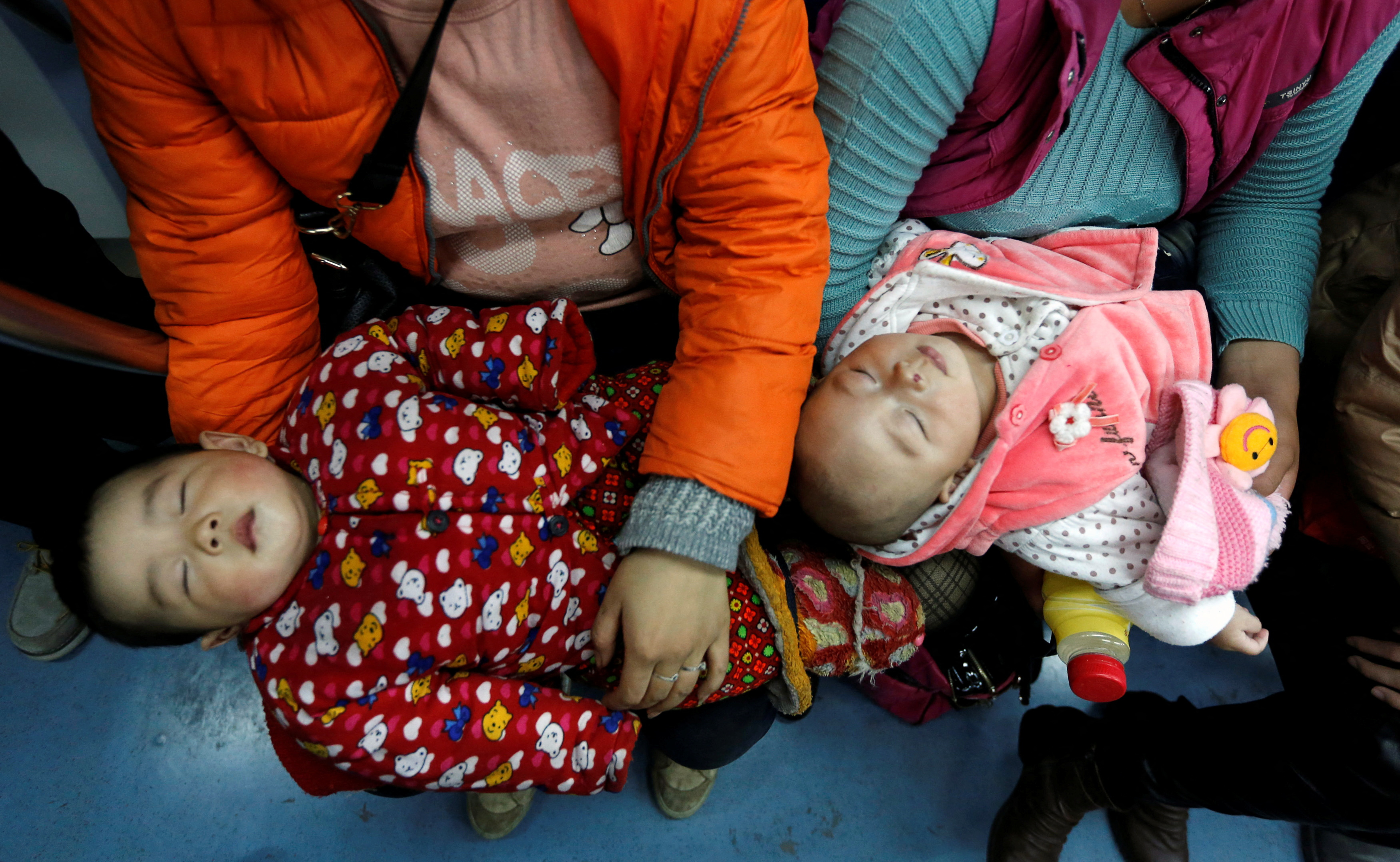 FILE PHOTO: Women hold their babies in a subway train in Beijing