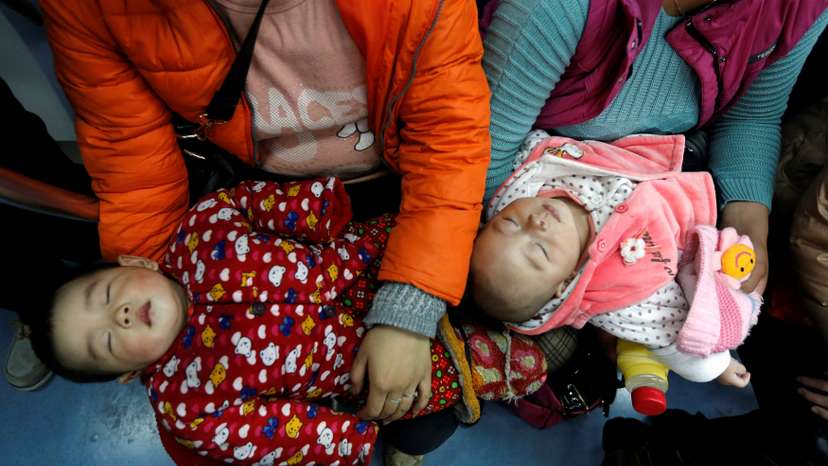FILE PHOTO: Women hold their babies in a subway train in Beijing