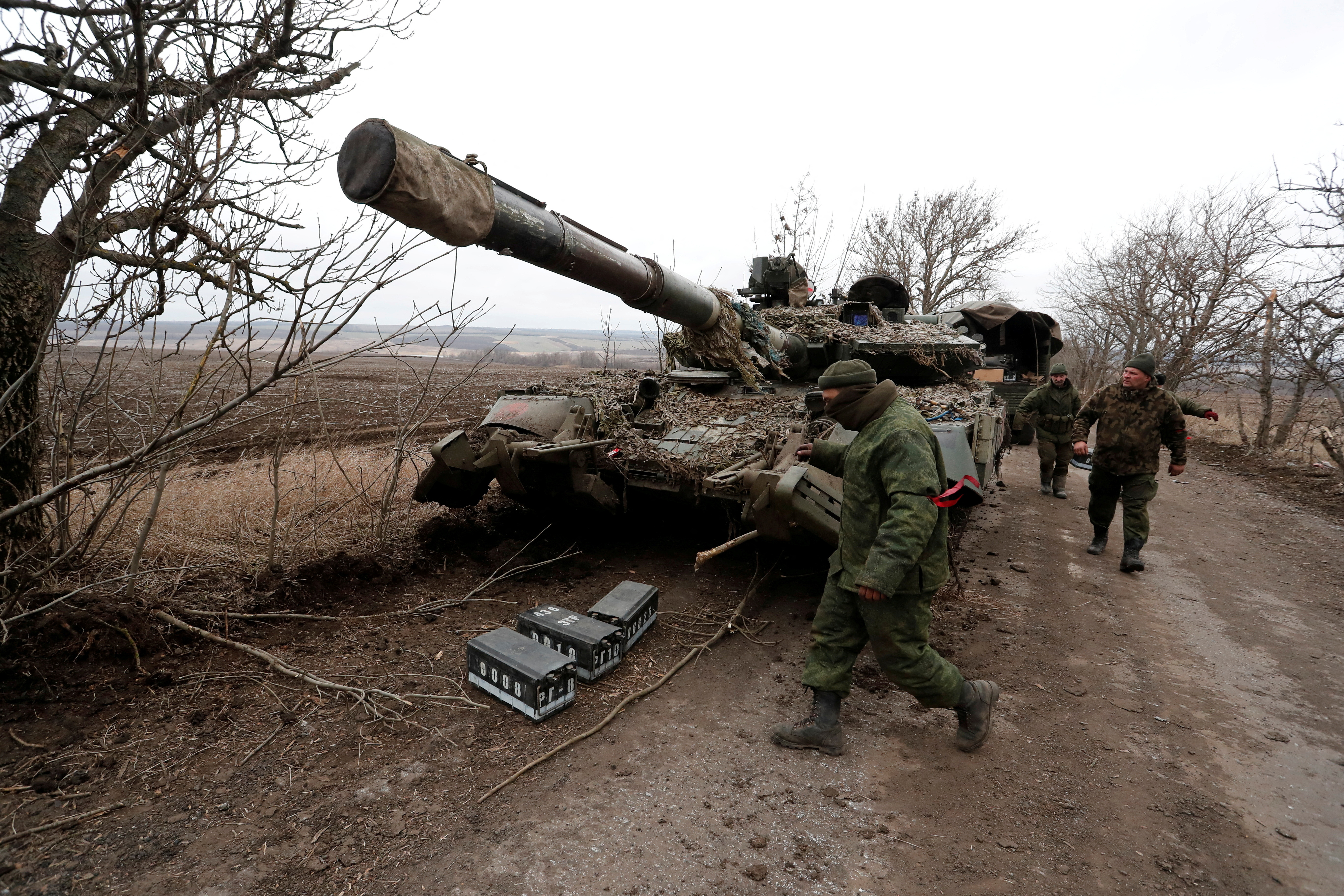 FILE PHOTO: Pro-Russian separatists walk near a tank in Donetsk region