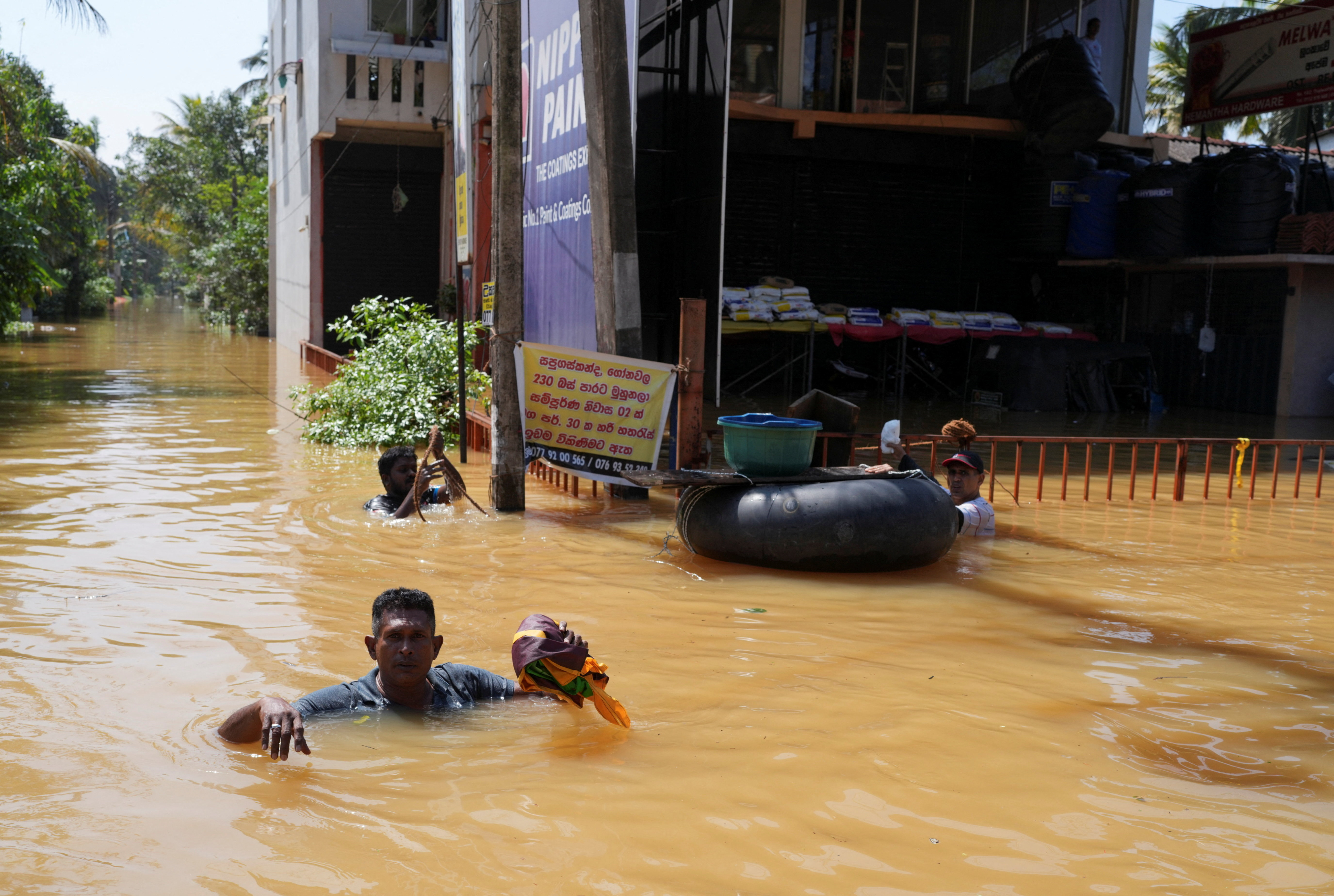 People wade through a flooded street, following Cyclone Ditwah in Kelaniya