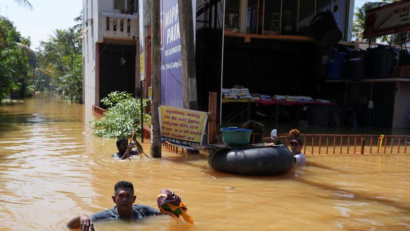 People wade through a flooded street, following Cyclone Ditwah in Kelaniya