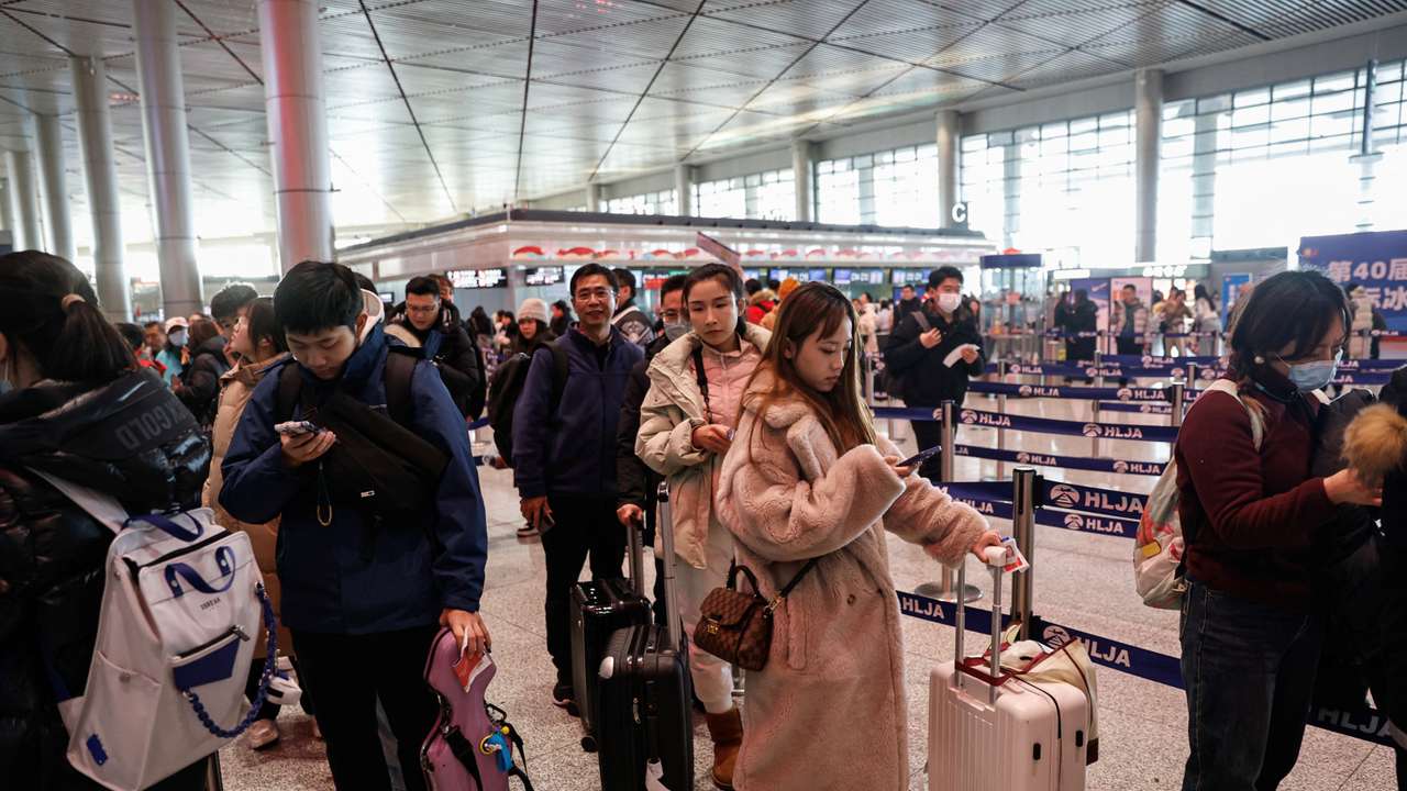 People wait in line to go through the security check at an airport in Harbin