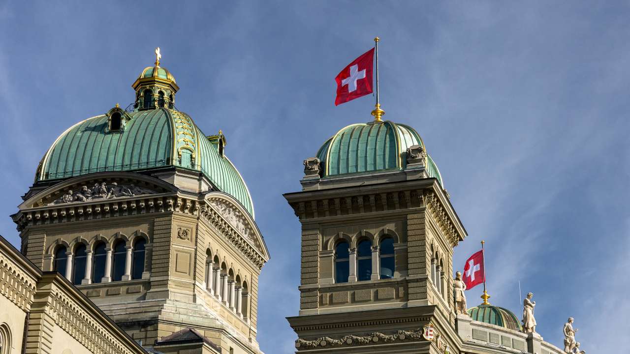 Swiss flags flutter on the Swiss Parliament Building (Bundeshaus) in Bern
