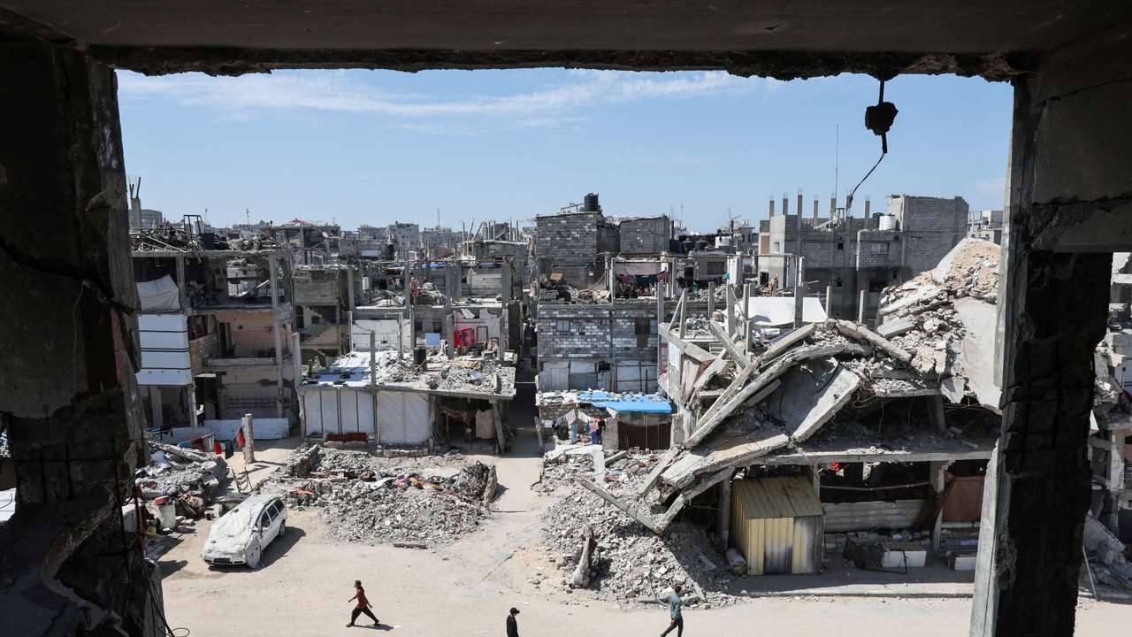 Palestinians walk near rubble of houses in Khan Younis