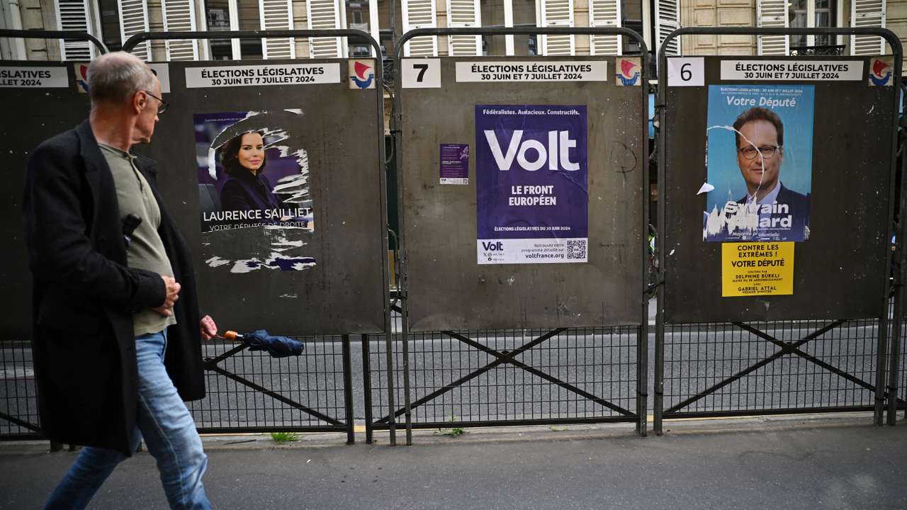 A man walks past election posters ahead of the French parliamentary elections in Paris