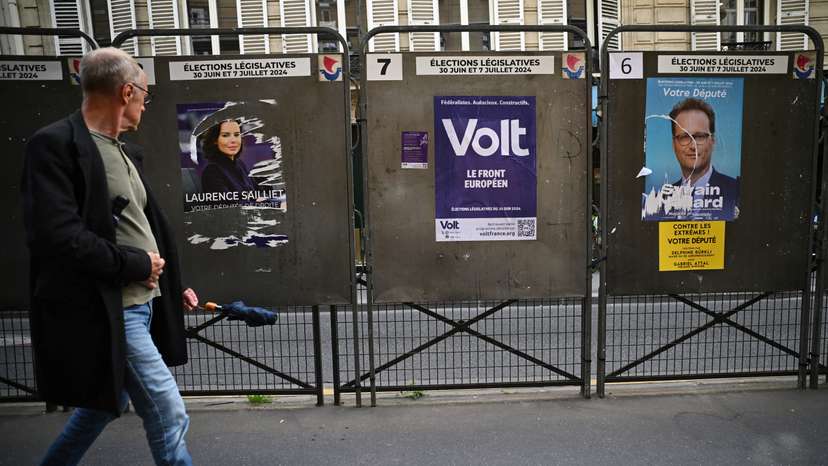 A man walks past election posters ahead of the French parliamentary elections in Paris