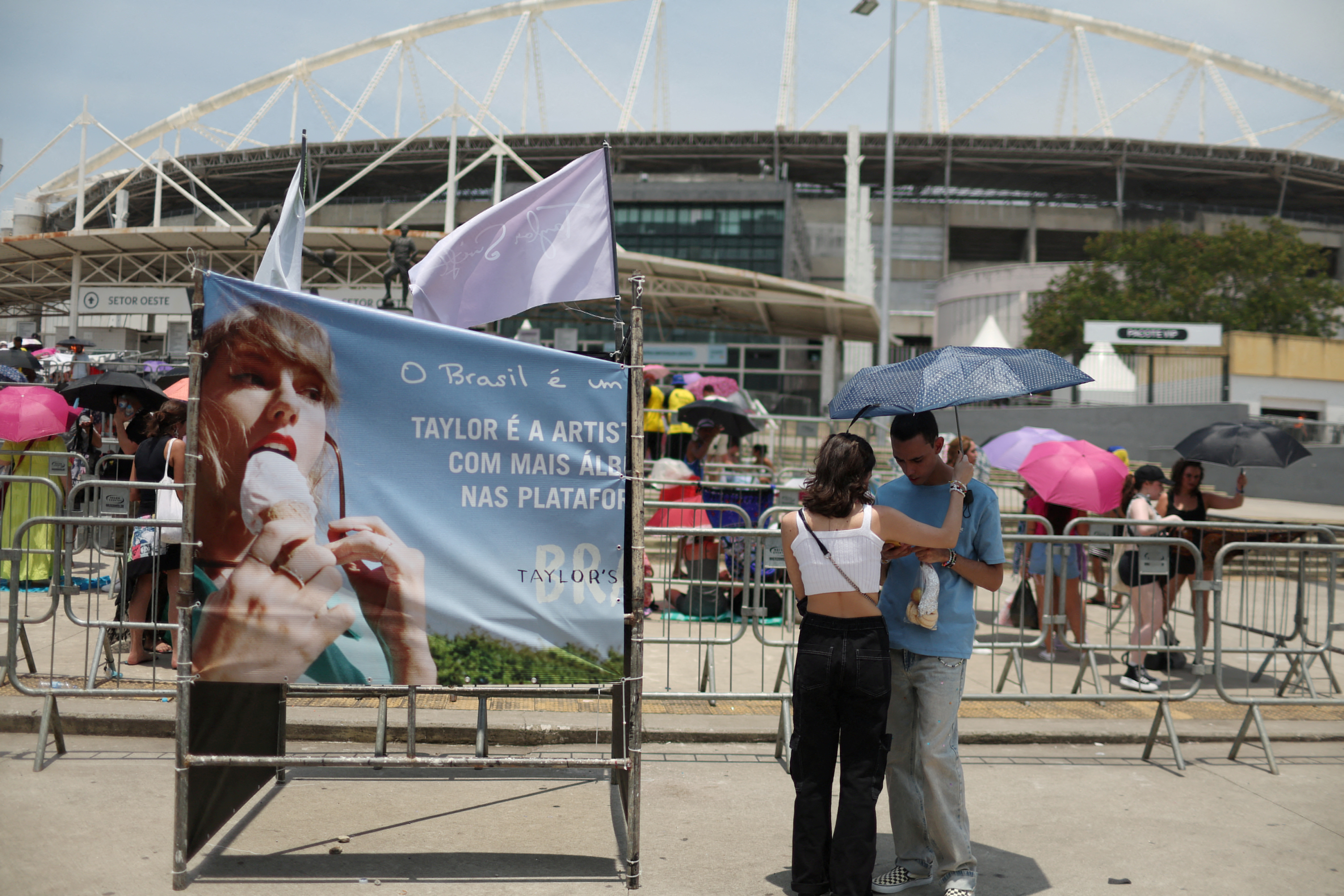FILE PHOTO: A couple protect themselves with an umbrella for high temperatures, wait before the Taylor Swift concert in Rio de Janeiro