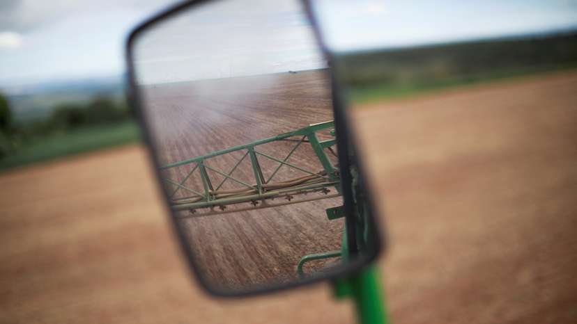 FILE PHOTO: A side-view mirror of a tractor shows herbicide being sprayed in a field of soybeans, near Brasilia