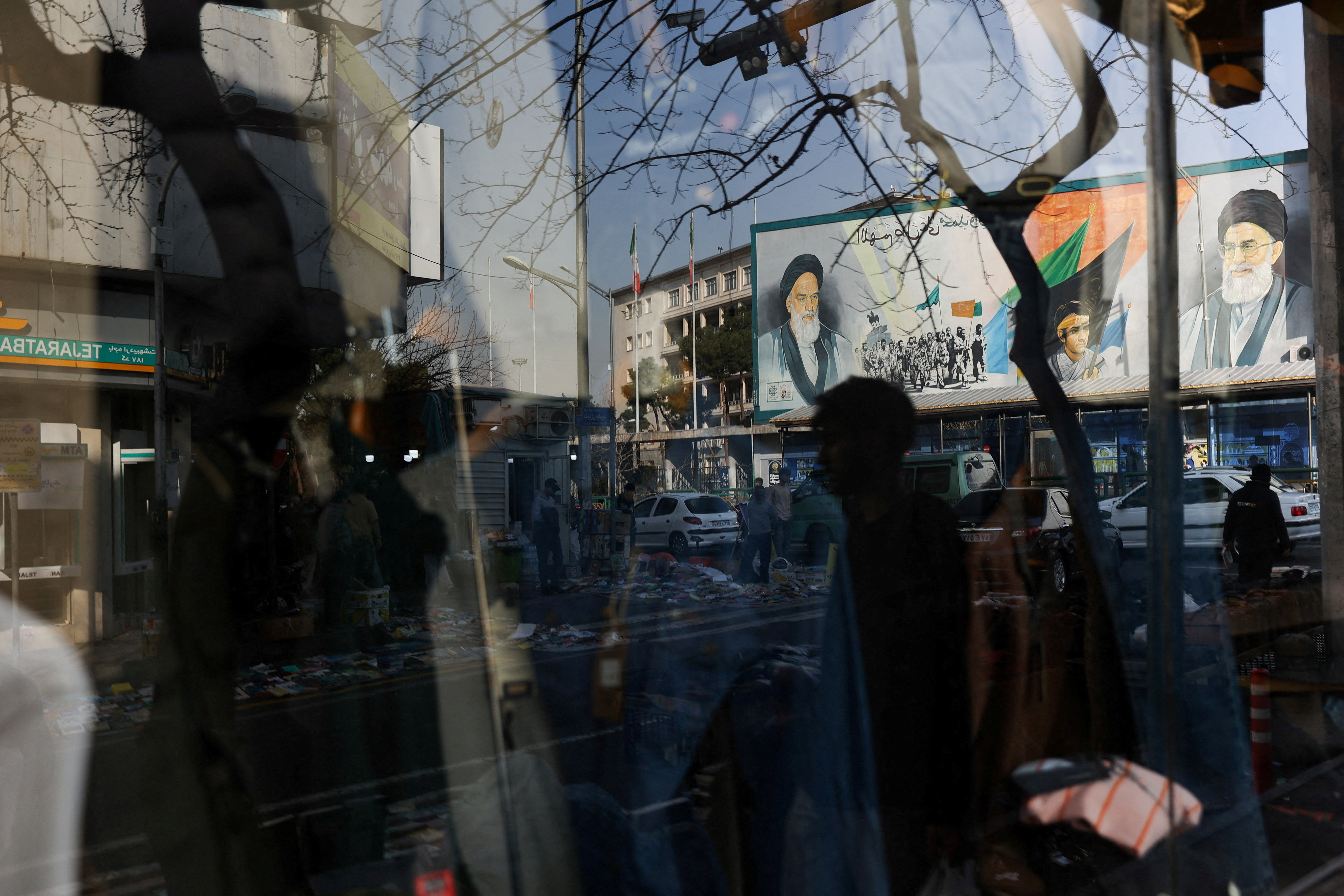 A sign with a depiction of Iran's Supreme Leader, Ayatollah Ali Khamenei, is reflected in a shop window in Tehran