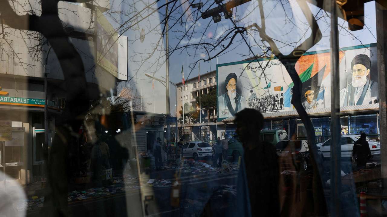 A sign with a depiction of Iran's Supreme Leader, Ayatollah Ali Khamenei, is reflected in a shop window in Tehran